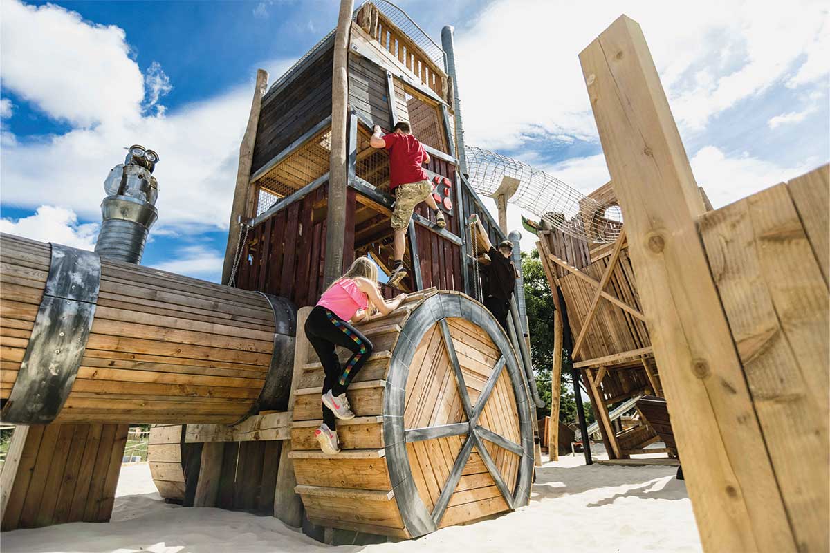 Colour photo of children climbing giant wooden tractor at Hobbledown Heath adventure playground