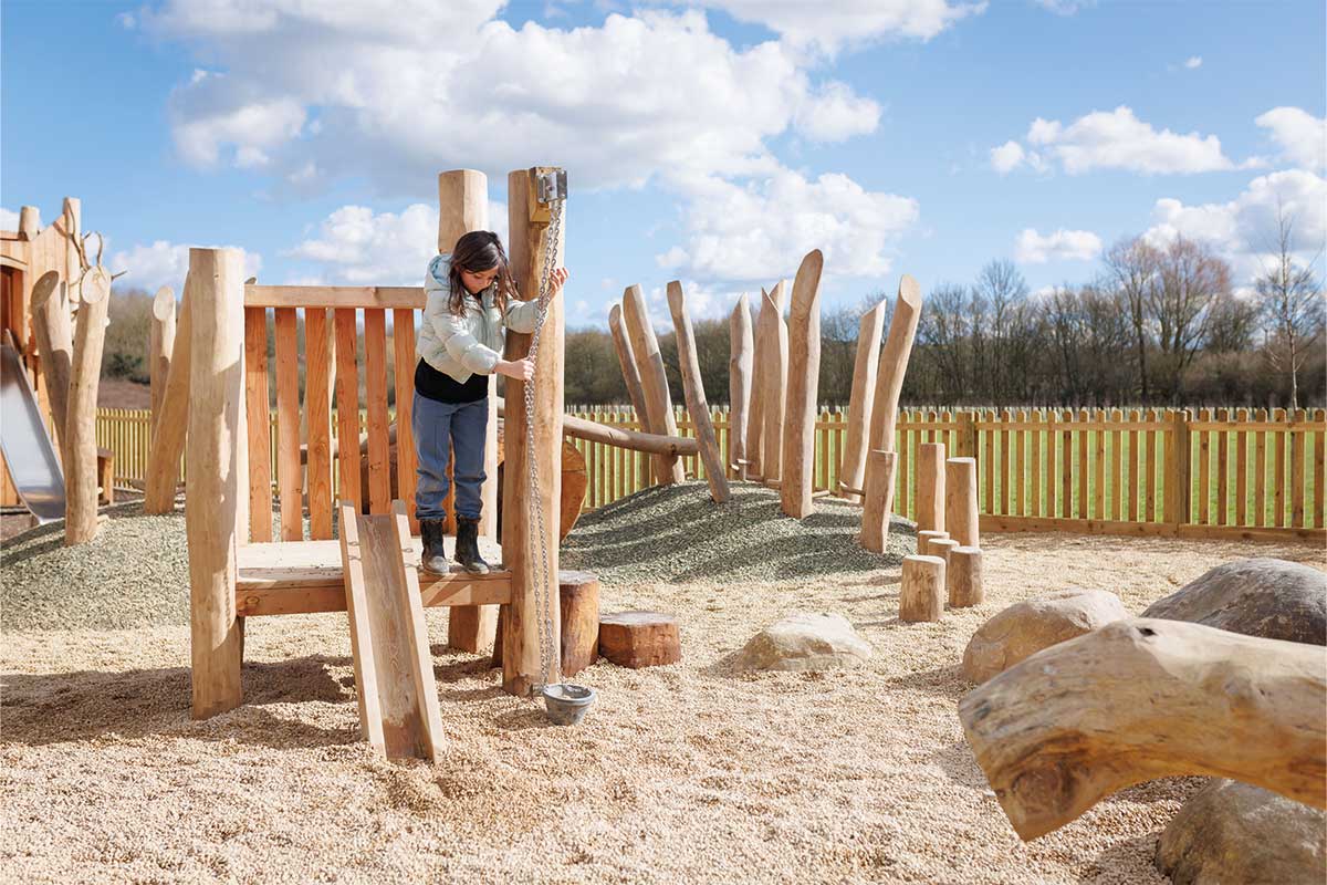 Colour photo of child playing with basket on wooden playground tower