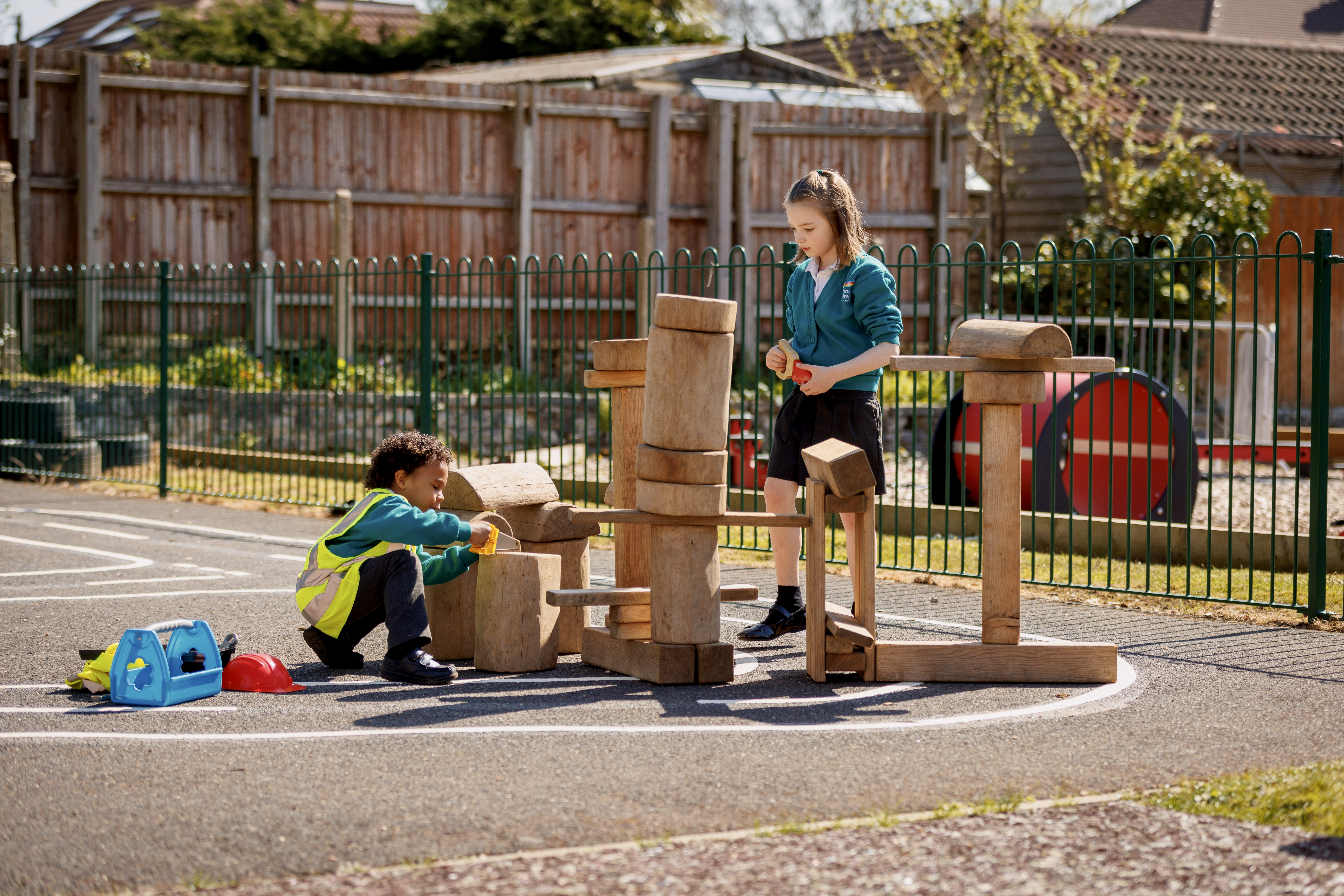 Colour photo of children playing with wooden building blocks in Stanley Green school playground