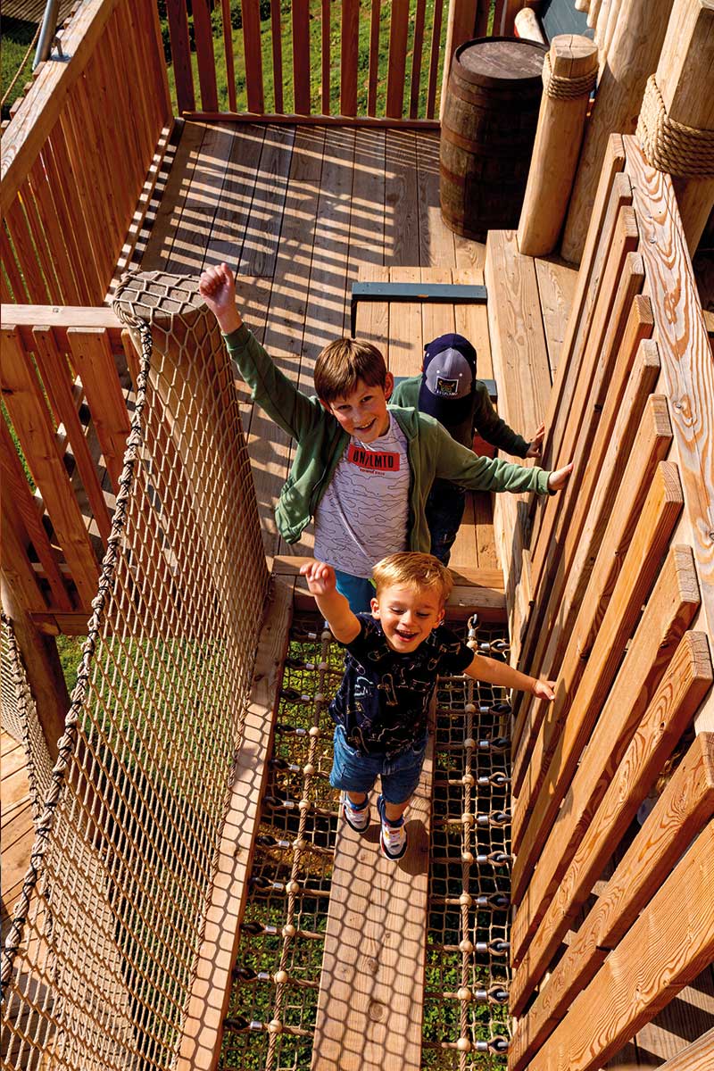 Colour photo of children smiling on wooden net bridge at Festyland theme park playground