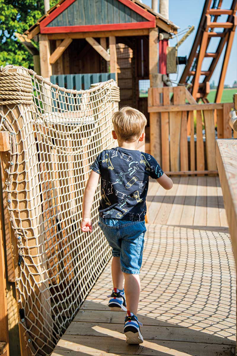 Colour photo of child running across wooden net bridge at Festyland theme park playground