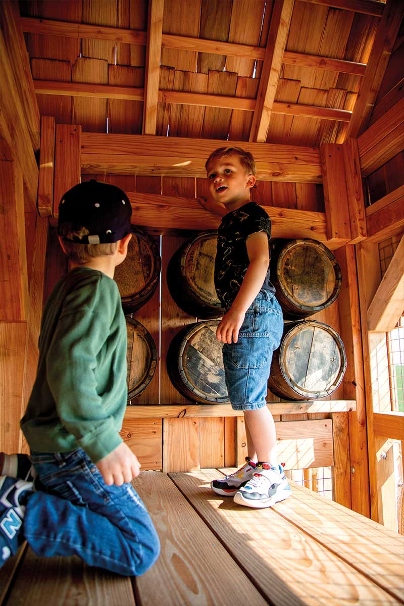 Colour photo of children playing in wooden tower with play barrels at Festyland theme park playground