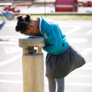 a girl looking into a magnifying post play equipment