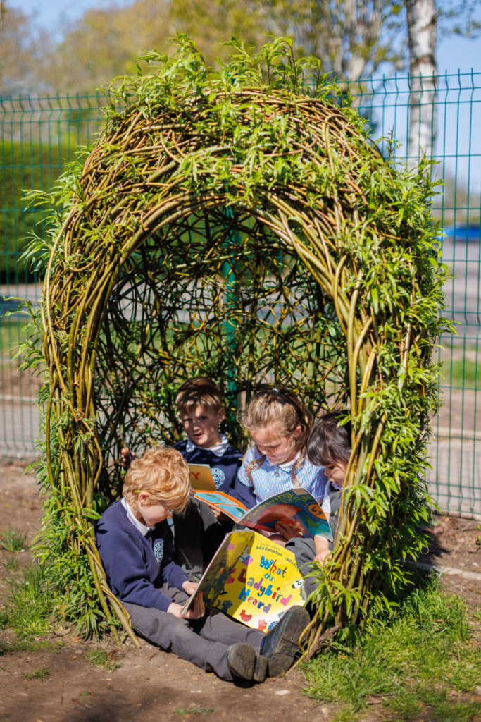 Four children sitting and reading books in a quiet area willow egg play structure 