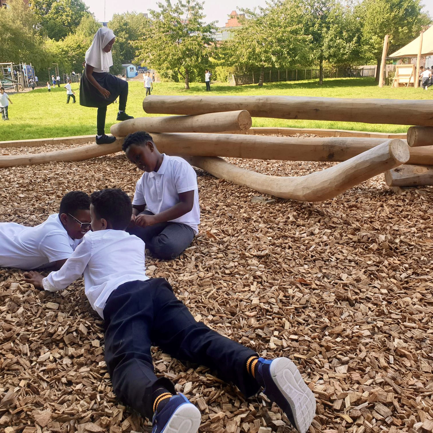 Children sitting and playing on a timber tangle climber play feature