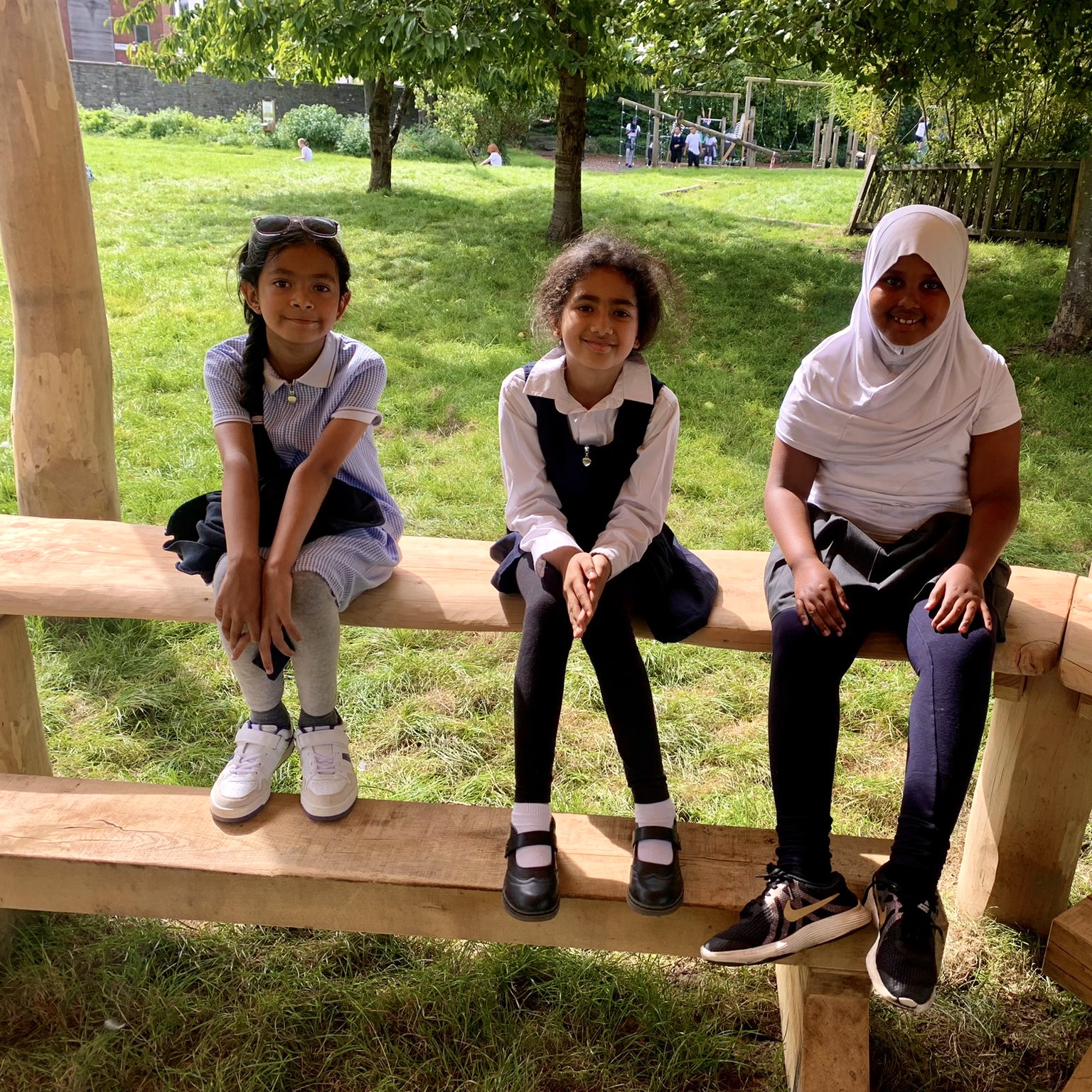 School pupils sitting on a bench under an outside classroom canopy 